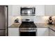 Modern kitchen with stainless steel appliances, white cabinets, and tile backsplash at 2360 S Troy Ct, Aurora, CO 80014