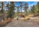 House exterior surrounded by trees with a gravel driveway at 5200 Parmalee Gulch Rd, Indian Hills, CO 80454