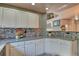 Updated kitchen with white cabinets, granite counters, and tile backsplash at 8016 E Fairmount Dr, Denver, CO 80230