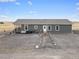 Rear view of a ranch home with a gravel yard and stone walkway at 1570 S County Road 129, Bennett, CO 80102