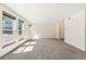 Sunlit living room with neutral walls and carpet, plus a door to the hallway at 1150 Inca St # 27, Denver, CO 80204