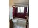 Bathroom with a tub, toilet and maroon tile at 3073 Zion St, Aurora, CO 80011