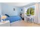 Bright blue bedroom with a twin bed, desk, and large window overlooking trees at 7999 E Vassar Dr, Denver, CO 80231