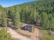 Aerial view showcasing a log cabin with solar panels in a forest setting at 9719 Beaver Pond, Conifer, CO 80433