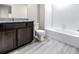 Bathroom with granite countertop, dark brown vanity, and white tile at 7302 Arkansas Street, Frederick, CO 80530