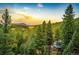 Aerial view of house nestled in a wooded mountain area at sunset at 32651 Buffalo Creek Rd, Evergreen, CO 80439