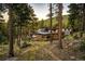 Back of house showing stonework, hot tub, and wooded surroundings at 32651 Buffalo Creek Rd, Evergreen, CO 80439