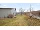 Side yard with grass, a tree, and a wooden fence at 305 Ravine Way, Brighton, CO 80603