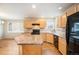 Kitchen with an island, light wood cabinets, and black appliances at 1631 Woodcock St, Berthoud, CO 80513