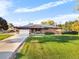 Brick ranch home with solar panels, attached garage, and a large front yard at 9941 Ammons Cir, Broomfield, CO 80021
