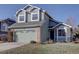 Two-story house with green siding, brick accents, and a two-car garage at 6945 S Dover Way, Littleton, CO 80128