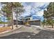 Modern two-story home with a gray exterior, wood accents, and a long driveway at 1298 Silverheels Dr, Larkspur, CO 80118