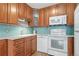 View of kitchen with wood cabinets, white appliances and light blue tile backsplash at 650 S Alton Way # 5D, Denver, CO 80247