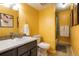 Yellow bathroom with a toilet, shower, and vanity with dark grey cabinets at 7525 W 62Nd Ave # 11, Arvada, CO 80003