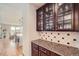 Butlers pantry with glass-front cabinets, granite countertop, and tile backsplash at 872 Eveningsong Dr, Castle Rock, CO 80104