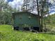 A green cabin with a deck and stairs, surrounded by trees and nature at 106 Brook Rd, Evergreen, CO 80439