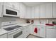 Bright eat-in kitchen, featuring white cabinetry, updated appliances, and tile backsplash at 9340 E Center Ave # 2C, Denver, CO 80247