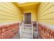 Front entry with brick and yellow siding, leading to a brown door at 4180 Combine Pl, Brighton, CO 80601