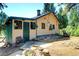 Charming yellow cottage with green trim, stone foundation, and landscaping at 5673 Santa Clara Rd, Indian Hills, CO 80454