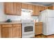 Kitchen with light wood cabinets, white appliances, and laminate flooring at 5726 N Genoa Way # 10-106, Aurora, CO 80019