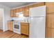 Kitchen boasts wood cabinets, white appliances, and a view into the laundry area at 5726 N Genoa Way # 10-106, Aurora, CO 80019