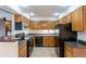 Galley kitchen with wood cabinets and black appliances at 201 Wright St # 106, Lakewood, CO 80228