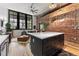 Open floor plan with exposed brick wall, modern kitchen island and living area at 2441 N Broadway # 106, Denver, CO 80205