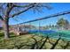 Tennis court with a net, surrounded by grass and trees at 13901 E Marina Dr # 109, Aurora, CO 80014