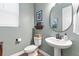 Stylish powder room with a pedestal sink, modern fixtures, and a round mirror at 3093 Belay Pt, Castle Rock, CO 80108