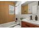 Updated bathroom with modern vanity, wood-look tile, and a shower/tub combo at 1529 Holly, Denver, CO 80220