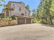 Two-car garage with modern doors and adjacent stone retaining wall at 26600 Mowbray Ct, Evergreen, CO 80439