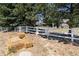 Hay bales sit in front of a white fence and home at 7846 Village Rd, Parker, CO 80134