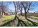 Large backyard with grass, mature trees, and a wooden fence at 1565 Xanthia St, Denver, CO 80220