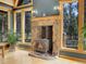 Stone fireplace with wood stove in a living room with large windows at 26526 Gray Buck Trl, Conifer, CO 80433