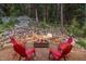Stone fire pit surrounded by red chairs in a wooded setting at 1003 Boreas Pass Rd, Breckenridge, CO 80424