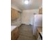 Kitchen with light wood cabinets, white appliances, and laminate flooring at 8031 Wolff St # H, Westminster, CO 80031