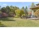 Landscaped backyard with patio, retaining wall, and mature trees at 6297 Ellingwood Point Way, Castle Rock, CO 80108