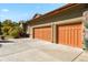 Three-car garage with orange doors and a large driveway at 6297 Ellingwood Point Way, Castle Rock, CO 80108
