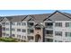 Three-story apartment building with gray siding and gray roof at 15700 E Jamison Dr # 8-203, Englewood, CO 80112