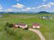 Aerial view showcasing a house, detached garage, and vast green landscape at 12155 Mesa View Rd, Larkspur, CO 80118
