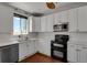 Galley kitchen with white cabinets, stainless steel appliances, and a window view at 3188 S County Road 137, Bennett, CO 80102