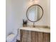 Charming powder room with wood vanity, round mirror, and updated fixtures at 3534 Running Deer Dr, Castle Rock, CO 80109