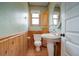 Small bathroom with pedestal sink, toilet, and wood-paneled walls at 209 10Th Ave, Idaho Springs, CO 80452