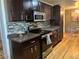 Modern kitchen with dark cabinetry, stainless steel appliances, and hardwood floors at 7625 W 23Rd Pl, Lakewood, CO 80214