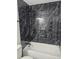 Bathroom with a bathtub and dark marble-style tile at 5387 Billings St, Denver, CO 80239