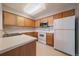 Galley kitchen with wood cabinets, white appliances, and double sink at 930 Button Rock Dr # J59, Longmont, CO 80504