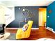 Bright living room with yellow armchair, geometric shelves, and hardwood floors at 10330 W Jewell Ave # A, Lakewood, CO 80232