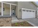 Front entry and attached two-car garage with gray siding and landscaping at 11076 Star Fall St, Littleton, CO 80125