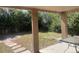 Covered patio overlooks a fenced backyard with a stone patio and mature trees at 1515 S Monaco Pkwy, Denver, CO 80224