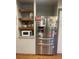 Stainless steel refrigerator and microwave in a galley kitchen with wood cabinets at 1515 S Monaco Pkwy, Denver, CO 80224